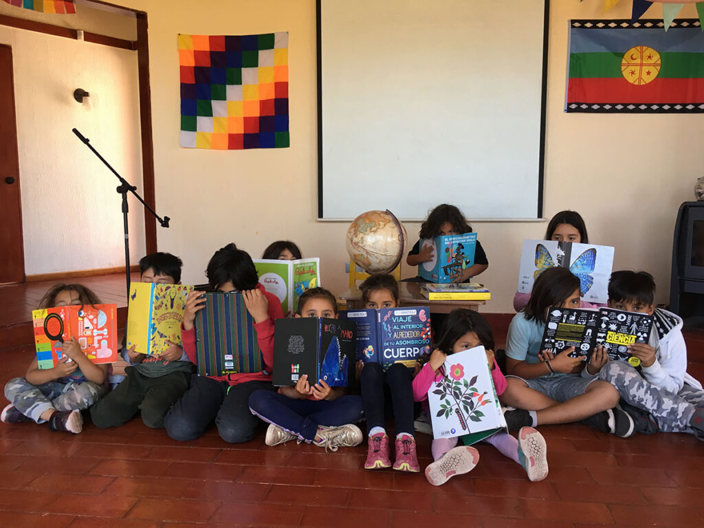 Niñas y niños leyendo libros ilustrados en la sala de la escuela