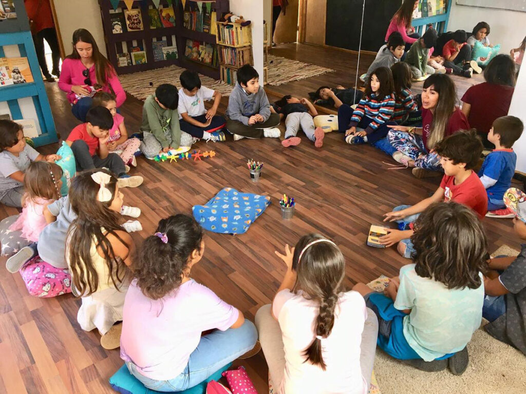 Ronda de niñas y niños sentados en el suelo de la sala