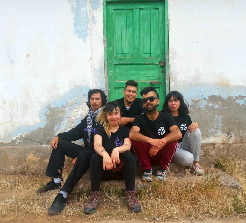 Integrantes del Laboratorio Creativo Remolino sentados frente a una puerta verde